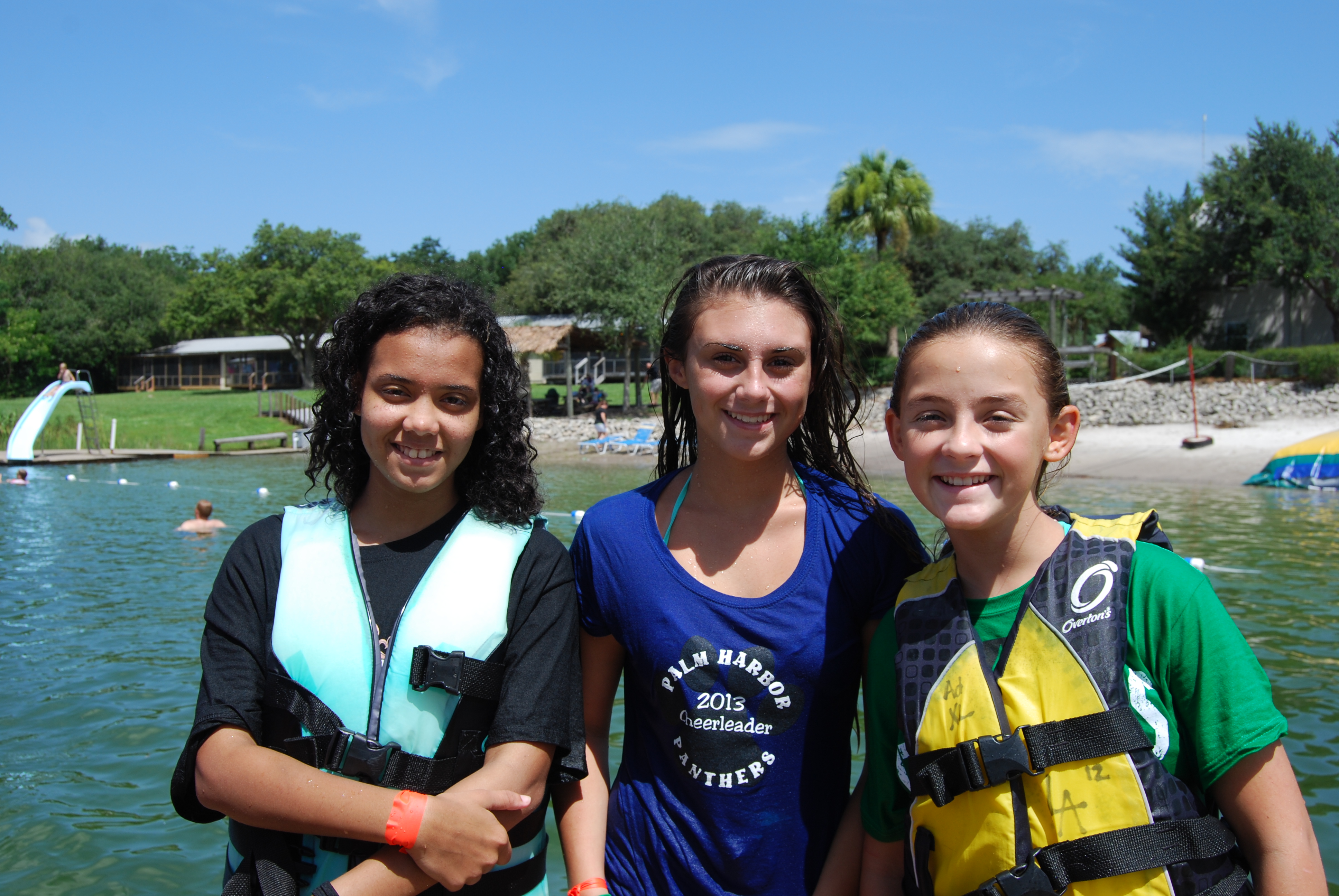 Three girl campers smiling on the lake